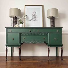 a green dresser with two lamps on top of it next to a painting and lamp shades