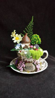 a teacup filled with flowers and plants sitting on top of a saucer covered in moss