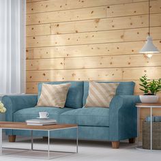 a blue couch sitting in front of a wooden wall next to a table with a coffee cup on it