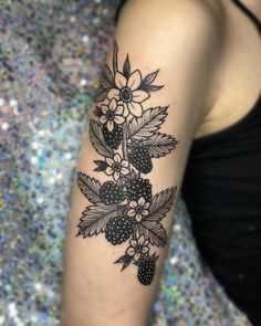 a woman's arm with black and white flowers on the left side of her arm