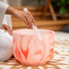 a woman is using an electric toothbrush to brush her teeth in a pink marbled bowl