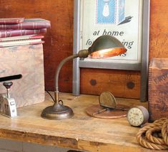 an old fashioned desk lamp sitting on top of a wooden table next to some books