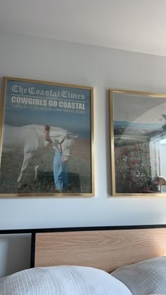 two posters on the wall above a bed in a room with white sheets and pillows