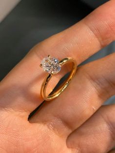 a woman's hand holding a gold ring with a diamond on the top and bottom