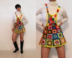 the woman is wearing a multicolored crocheted skirt and boots with her hands on her hips