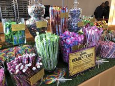 there are many candy and candies on display at the table with price tags for them