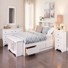 a white bed with drawers underneath it and a mirror on the wall next to it