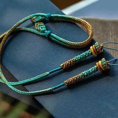 a pair of blue and gold bracelets sitting on top of a book with two strings attached to it