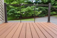 a wooden deck with metal railings and trees in the backgroung area