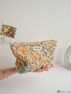 a hand holding a small purse made out of fabric