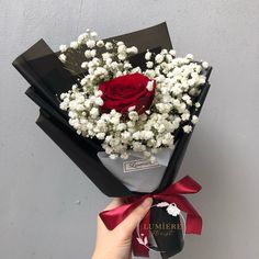 someone is holding a bouquet of flowers in front of a wall with a name tag on it