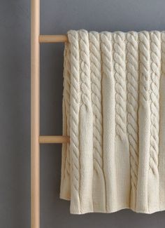 a white knitted blanket hanging on a wooden rack