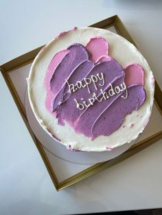 a birthday cake with pink and purple frosting in a gold frame on a table