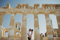 two people standing next to each other in front of columns