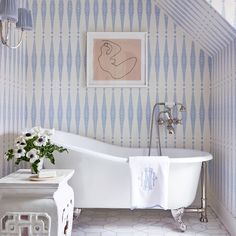 a white bath tub sitting in a bathroom next to a painting on the wall above it