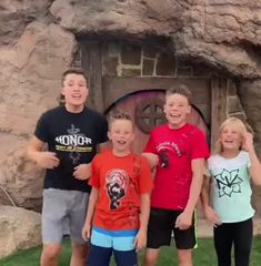 four children are standing in front of a cave