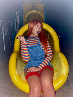 a woman with red hair sitting on a yellow tube in fish net stockings and tights