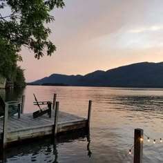 a dock on the edge of a lake with lights hanging from it's posts