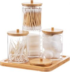 three jars with toothpicks and cotton swabs in them on a wooden tray