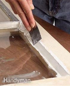 a person is using a knife to cut through the edge of a window