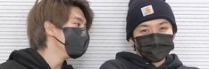 two people wearing face masks in front of a wall