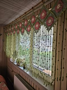 a window with beads hanging from it's sides and flowers on the windowsill