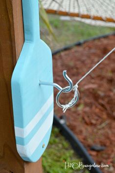 a blue and white clock hanging from the side of a wooden fence next to a hammock