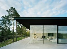 an open room with glass walls and white furniture on the outside, surrounded by trees