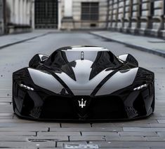 a black and white sports car parked on the side of a brick road in front of a building