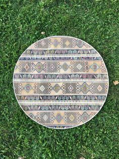 a person standing in the grass next to a round rug