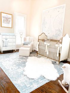 a baby's room with white furniture and blue rugs on the wooden floor