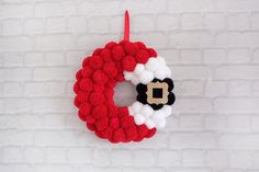 a red and white christmas wreath hanging on a brick wall next to a black and white santa clause ornament