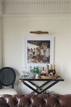 a leather couch sitting next to a table with bottles and glasses on top of it