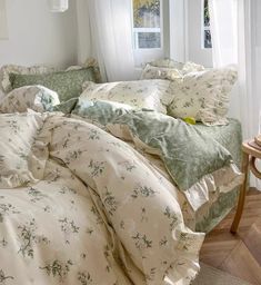 an unmade bed with green and white comforter in a bedroom next to a window