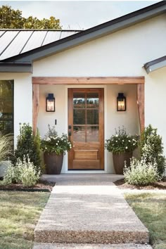 the front door of a house with two planters on each side and an entry way