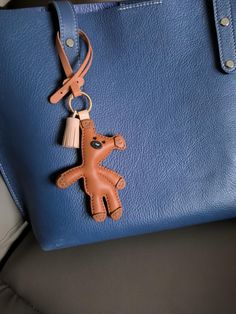 a blue handbag with a brown teddy bear keychain hanging from it's side