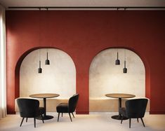 two round tables with black chairs in front of red and white walls that have arched windows