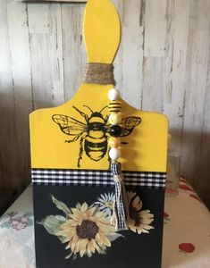 a wooden sign with a bee and sunflower painted on it's front side