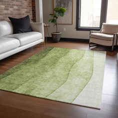 a living room filled with furniture and a green rug on top of a hard wood floor