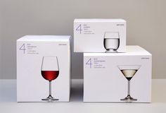 three wine glasses sitting next to each other in front of boxes on a table top