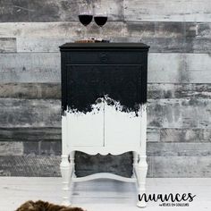 a black and white painted cabinet next to a brown fur rug on the floor in front of a wooden wall