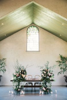 a wedding ceremony setup with candles and flowers on the alter, in front of a stained glass window