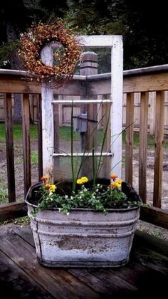 a potted planter with flowers in it sitting on a deck next to a wooden fence