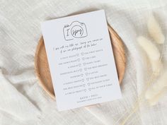 a wooden plate with a white card on top of it next to some dry grass