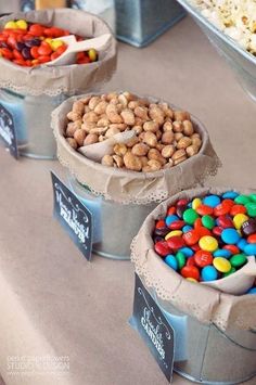 three buckets filled with different types of candies on top of a buffet table