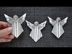 two origami angels made out of one dollar bill are being held by someone's hand