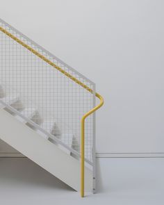 a white stair case next to a yellow hand rail on the side of a wall