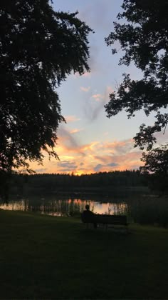 a person sitting on a bench in front of a lake