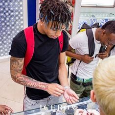 a man with dreadlocks standing in front of a display case at a store