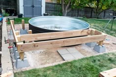 a large metal tub sitting on top of a wooden platform in the middle of a yard